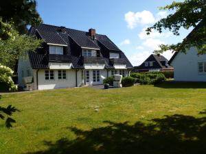 una casa blanca con techo negro y patio en Haus Heide Hüs, App 2, en Wenningstedt
