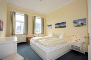 a bedroom with a white bed and two windows at Haus Decker, App 2 in Wenningstedt