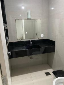 baño con lavabo negro y espejo en Apartamento de frente para o mar, en Guarapari