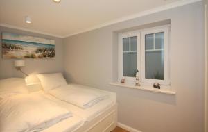 a white bedroom with a bed and two windows at Düne 20 in Westerland (Sylt)