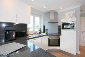 a kitchen with white cabinets and black counter tops at Düne 20 in Westerland (Sylt)