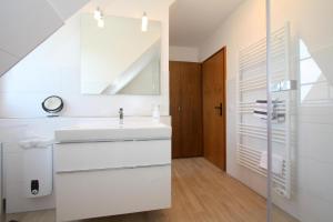ein weißes Badezimmer mit einem Waschbecken und einer Treppe in der Unterkunft Jutta, App 6 in Wenningstedt-Braderup