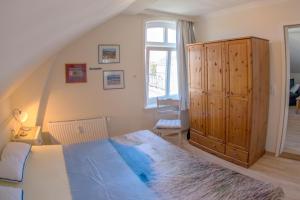 a bedroom with a large bed and a wooden cabinet at Sölring Hüs, App 4 in Wenningstedt
