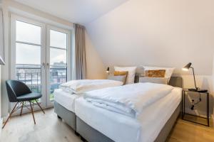 a bedroom with two beds and a chair and a window at Strandgut Wohnung 7 in Wenningstedt