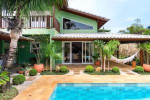 una casa con piscina frente a ella en UBATUBA PRAIA DO SAPE - bela casa em condominio - 01 Quadra da Praia, Wifi, Piscina, Churrasqueira e Forno de Pizza, en Ubatuba