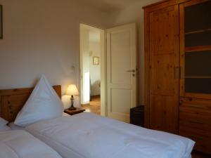 ヴェニングシュテットにあるLH Heidegrund, App 2の白いベッドと木製クローゼット付きのベッドルーム1室
