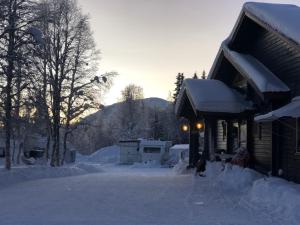 una persona sentada en la nieve junto a una cabaña en Camp Borga, en Borgafjäll