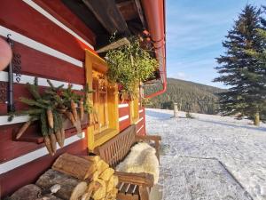 une cabine dans la neige avec un banc et une fenêtre dans l'établissement Chalupa U Kohoutů, à Pec pod Sněžkou