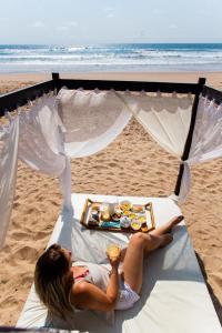 a woman laying on a bed on the beach at Rumah Pousada in Barra Grande