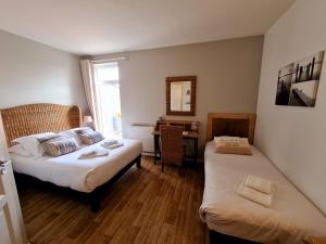a bedroom with two beds and a desk with a mirror at Logis Hôtel La Chaize in Noirmoutier-en-l'lle