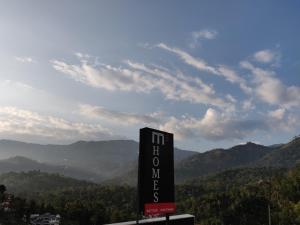 a sign for a hotel on top of a mountain at M3 Homes in Munnar