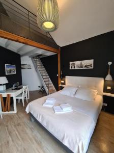 Un dormitorio con una gran cama blanca y una escalera en Logis Hôtel La Chaize, en Noirmoutier-en-l'Île