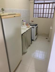 a white kitchen with a refrigerator and a stove at Kitnet - Apart Hotel 3 in Sete Lagoas