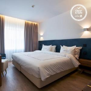 une chambre avec un grand lit et une tête de lit bleue dans l'établissement Hotel Moutados, à Vila Nova de Famalicão
