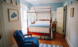 a bedroom with a bed and a blue chair at The Belmont Inn in Camden
