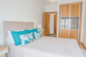 a bedroom with a large white bed with blue pillows at Perola Mar in Nazaré