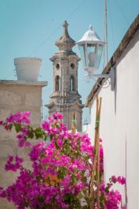 a building with a clock tower with pink flowers at HolidayMonopoli in Monopoli