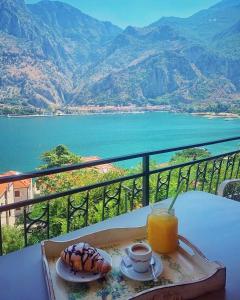 een tafel met een dienblad met eten en een glas sinaasappelsap bij Apartments Dončić in Kotor