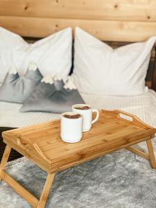 due tazze di caffè su un vassoio di legno su un letto di U Maćka a Białka