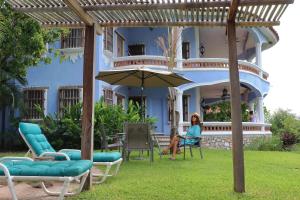 a woman sitting under an umbrella in front of a house at Bungalows Santa Cruz in Puerto Escondido
