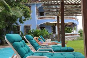 a couple of people laying on lounge chairs by a pool at Bungalows Santa Cruz in Puerto Escondido