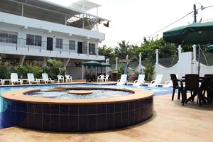 梅爾加的住宿－Hotel Cacique Guaicani，一个带游泳池和桌椅的度假酒店