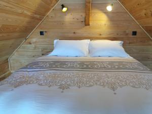 Bett in einem Zimmer mit Holzwänden in der Unterkunft Les cabanes du domaine de l Esperluette in Le Lauzet-Ubaye