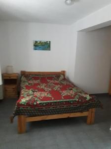 Una cama en una habitación con una manta roja. en La Nona en Villa Cura Brochero