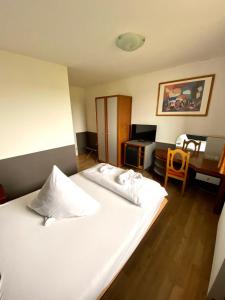 a bedroom with a large white bed and a desk at Hotel Castellana in Lessien