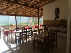 a dining room with a table and chairs and windows at Aconchego Canastra Hotel in Vargem Bonita