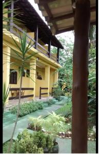 a yellow building with a palm tree in front of it at Pousada Rio Bracuhy in Angra dos Reis