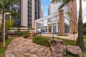 a park with a bench and palm trees and buildings at Maximus Luxury NYC Berrini II in Sao Paulo