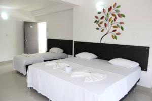 梅爾加的住宿－Hotel Cacique Guaicani，墙上有一棵树的房间,配有两张白色的床