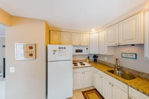 a kitchen with white cabinets and a refrigerator at Sea Pirate 1 in Holmes Beach