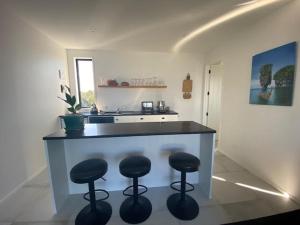 a kitchen with a counter with three bar stools at Dune View Accommodation in Mangawhai