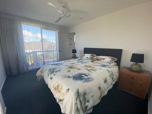 a bedroom with a bed with a floral bedspread at Dune View Accommodation in Mangawhai