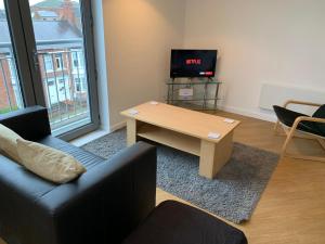 a living room with a coffee table and a tv at Central Darlington Apartment With Parking in Darlington
