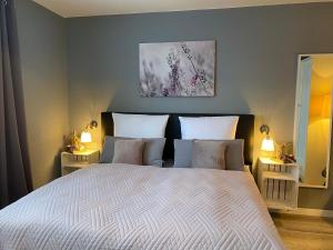 a bedroom with a large bed with two lamps at Pension Haus am Wald in Braunlage