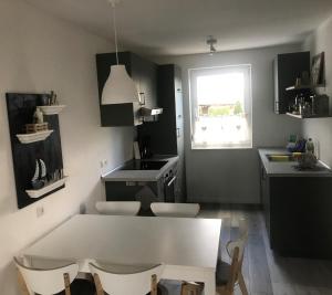 a kitchen with a white table and chairs and a window at Boddenhus Loissin in Loissin