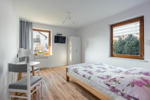 a bedroom with a bed and a desk and a window at Enklawa u Zosi in Szczawnica