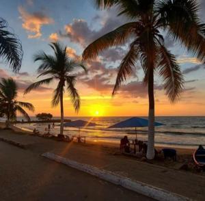a sunset on the beach with palm trees at AquaMarina Hostal in Tolú