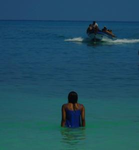 AquaMarina Hostal في تولو: امرأة تقف في المحيط مع قارب في الماء