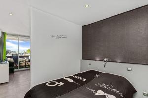 a bedroom with a bed with a black blanket on it at Village Naturiste - Le Caresse Port Nature Luxe in Cap d'Agde