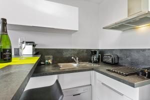 a kitchen with a sink and a bottle of wine at Village Naturiste - Le Caresse Port Nature Luxe in Cap d'Agde