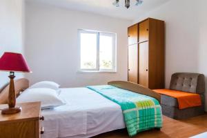 a bedroom with a bed and a chair and a window at Apartments AnteV - 80m from the sea in Sevid
