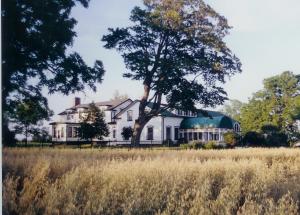 ein großes weißes Haus mit einem Baum auf einem Feld in der Unterkunft Stevenson Farms-Harvest Spa B & B in Alliston