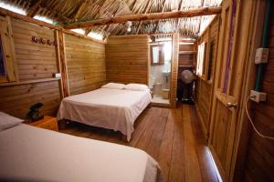 Cabañas El Arca في تييرا بومبا: غرفة نوم بسريرين في كابينة خشبية