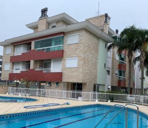 a building with a swimming pool in front of a building at VG-Excelente apto em Praia dos Ingleses, Florianópolis, SC in Florianópolis