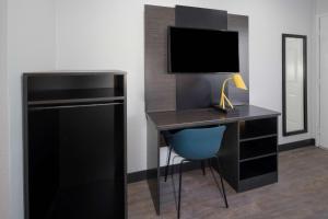een bureau met een televisie en een blauwe stoel in een kamer bij Motel 6-Fontana, CA in Fontana