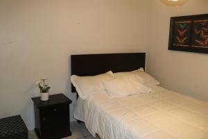 - une chambre dotée d'un lit avec des draps blancs et une tête de lit noire dans l'établissement LUGAR DE DESCANSO, à Ica